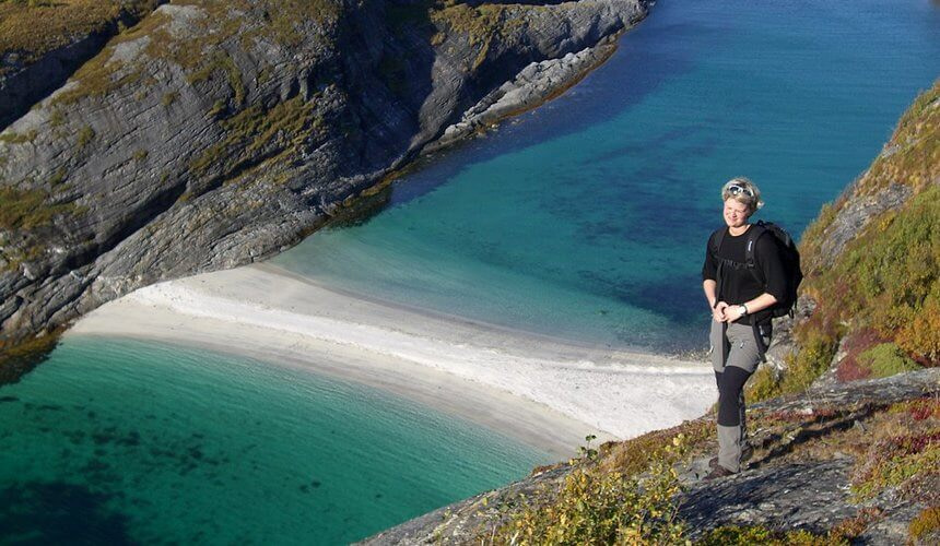Spiaggia di Hovsdundet e donna in posa mentre fa escursionismo sul percorso a strapiombo sulla spiaggia, Norvegia aurora boreale